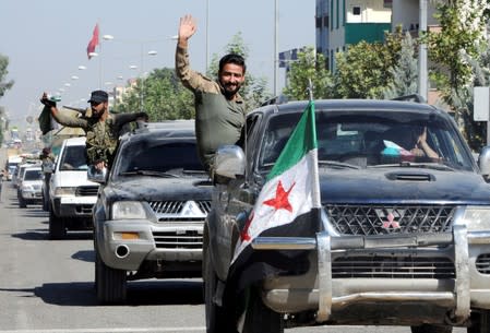 Members of Syrian National Army, known as Free Syrian Army, wave as they drive to cross into Syria in the Turkish border town of Akcakale