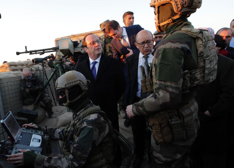 French President Francois Hollande and French defense minister Jean-Yves Le Drian, center right, meet with French soldiers as they visit a military outpost on the outskirts of Islamic State-held city of Mosul, outside the Kurdish city of Irbil, Iraq, Monday, Jan. 2, 2017. Hollande is in Iraq for a one-day visit. (AP Photo/ Christophe Ena, Pool)