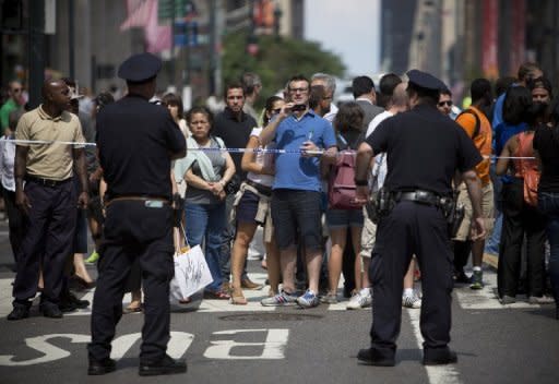 Transeúntes y curiosos se acercan al lugar del tiroteo, donde la policía les impide el paso, este viernes en Nueva York