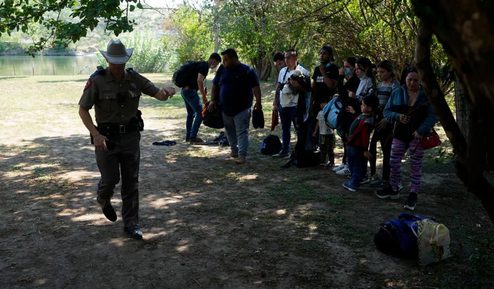 FILE - In this June 16, 2021 file photo, Texas Department of Public Safety officers work with a group of migrants who crossed the border and turned themselves in Del Rio, Texas. Republican Texas Gov. Greg Abbott's newest immigration crackdown, allowing state troopers to pull over vehicles suspected of carrying migrants on the basis that they could increase the spread of COVID-19 in the U.S., brought swift backlash from the Justice Department as criticism of the order mounted.