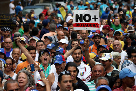 Demonstrators rally against Venezuela's President Nicolas Maduro carrying a sign that reads "No more dictatorship" in Caracas, Venezuela, April 13, 2017. REUTERS/Carlos Garcia Rawlins