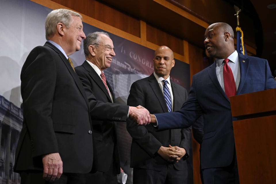 Sen. Tim Scott, R-S.C., right, turns back to shake hands with Sen. Chuck Grassley, R-Iowa, second from left, during a news conference on Capitol Hill in Washington, Wednesday, Dec. 19, 2018, on prison reform legislation. A criminal justice bill passed in the Senate gives judges more discretion when sentencing some drug offenders and boosts prisoner rehabilitation efforts. They are joined on stage by Sen. Dick Durbin, D-Ill., left, and Sen. Cory Booker, D-N.J., second from right. (AP Photo/Susan Walsh)