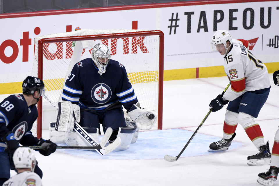 Winnipeg Jets goaltender Connor Hellebuyck (37) makes a save on Florida Panthers' Anton Lundell (15) during the second period of an NHL hockey game, Tuesday, Jan. 25, 2022 in Winnipeg, Manitoba. (Fred Greenslade/The Canadian Press via AP)