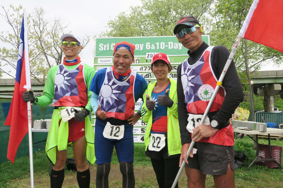 台灣跑者魏嘉鴻（右起）、蔡文雅、鍾運華及王萬仁27日完成在紐約皇后區法拉盛草原可樂娜公園舉行的10天超級馬拉松賽，在成績板前合影。（中央社）