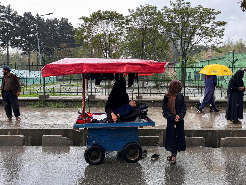 2023年4月18日，阿富汗喀布爾街頭，可看見街上女性都穿著全身罩袍，一名婦女抱著兒子坐在推車上。路透社