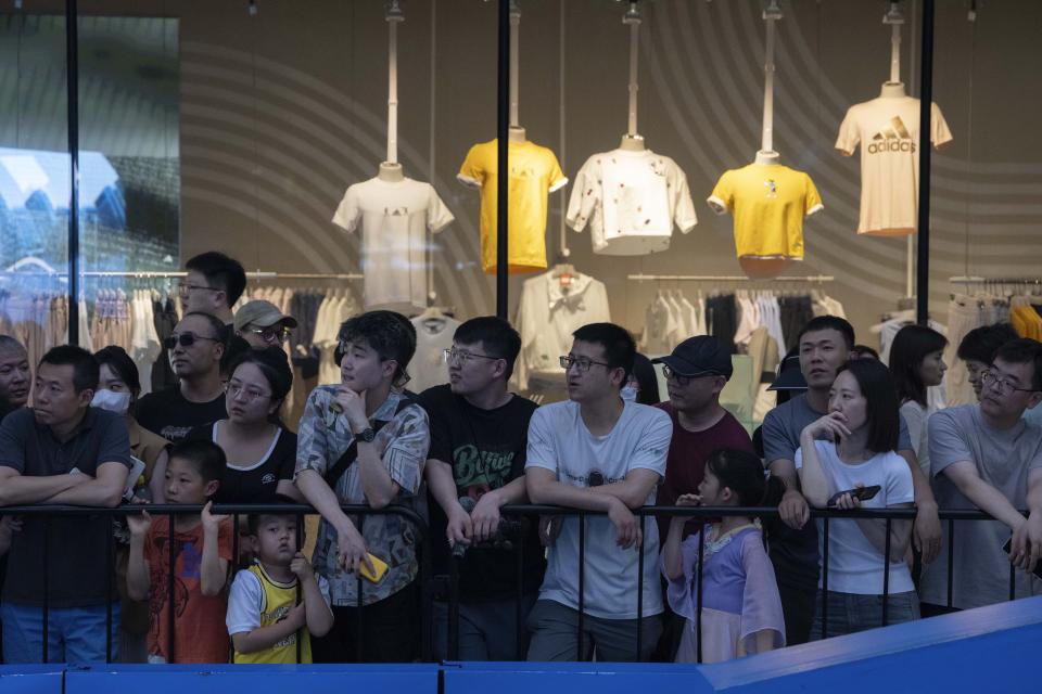 Shoppers watch a skating competition outside a shopping mall in Beijing, Sunday, June 18, 2023. Chinese merchants offered customers steep discounts during China's first major online shopping festival after the COVID-19 pandemic, in the hopes of shoring up sales amid a weaker-than-expected recovery in consumption. (AP Photo/Ng Han Guan)