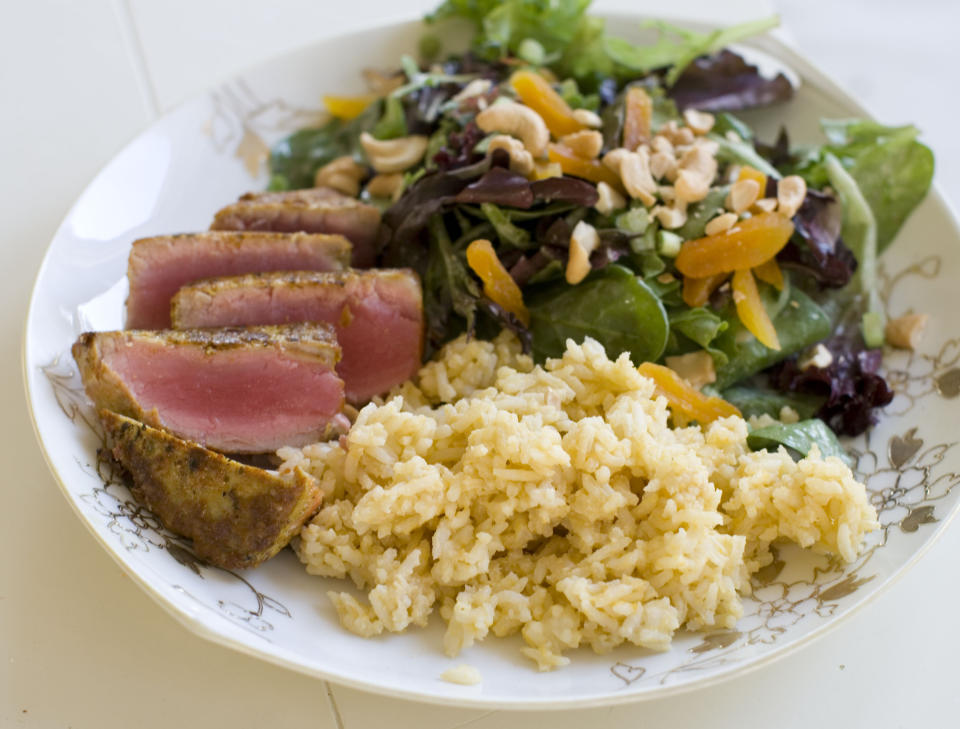 This Nov. 18, 2013 photo shows coconut cashew salad with apricots and seared curry rubbed tuna with mango tahini rice in Concord, N.H. It's a mash-up that draws on the flavors of the Caribbean, Southeast Asia and Europe. (AP Photo/Matthew Mead)