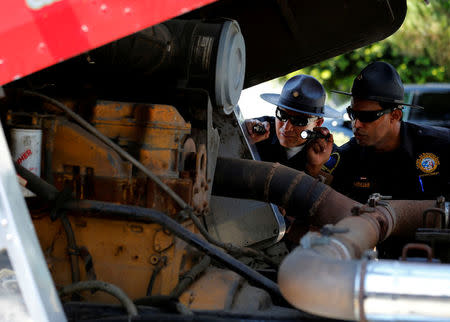 FILE PHOTO: California Air Resources field representative Valente Armenta (L) and Jose Andujar look into the engine of a truck as they work a checkpoint set up to inspect heavy-duty trucks traveling near the Mexican-U.S. border in Otay Mesa, California September 10, 2013. REUTERS/Mike Blake/File Photo
