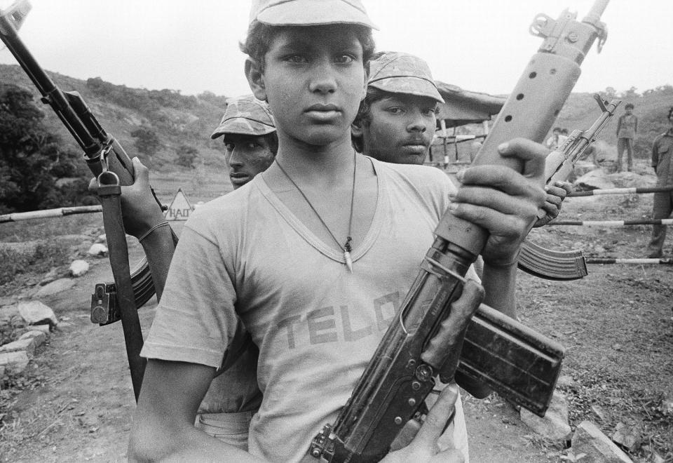 FILE- Three Tamil teenagers pose with their weapons a week before going for training in a camp in southern India, Nov. 10, 1986. (AP Photo/Liu Heung Shing, File)wld
