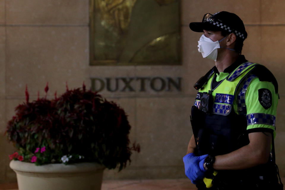 A police officer looks on as Australian passengers from Italian cruise liners arrive at the Duxton Hotel in central Perth. Source: AAP