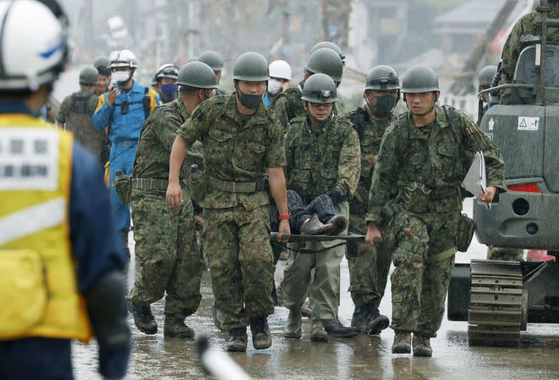 Japanese Self-Defence Force soldiers carry rescured person using a stretcher at a flooding site caused by a heavy rain in Kuma village