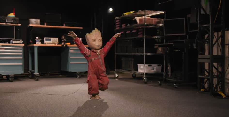 A baby Groot animatronic in a red jumpsuit jumping around
