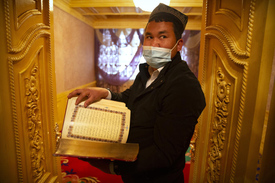 Tursunjan Mamat holds a copy of the Quran in the Arabic and Uyghur languages during a government organized visit for foreign journalists to his home in Aksu in western China's Xinjiang Uyghur Autonomous Region on April 20, 2021. Under the weight of official policies, the future of Islam appears precarious in Xinjiang, a remote region facing Central Asia in China's northwest corner. Outside observers say scores of mosques have been demolished, which Beijing denies, and locals say the number of worshippers is on the decline. (AP Photo/Mark Schiefelbein)