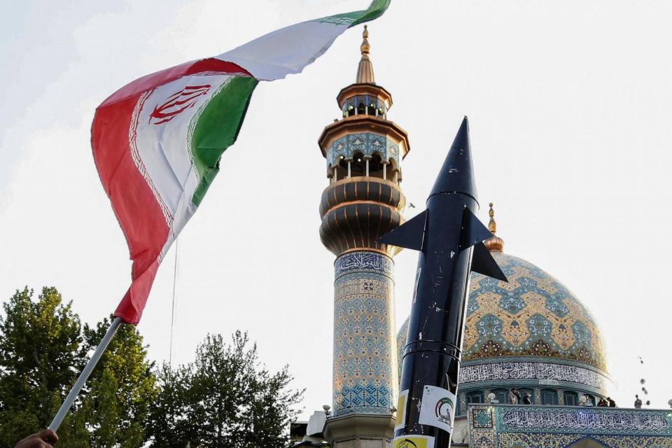 PHOTO: Iranian lift up a flag and the mock up of a missile during a celebration following Iran's missiles and drones attack on Israel, on April 15, 2024, at Palestine square in central Tehran. (Atta Kenare/AFP via Getty Images)