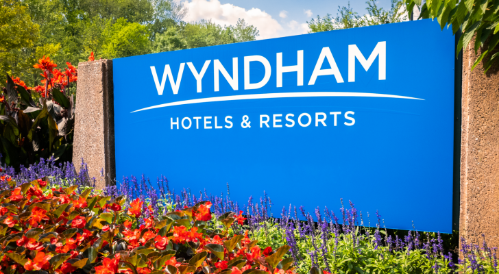 A blue sign says Wyndham Hotels & Resorts in front of red and purple flowers