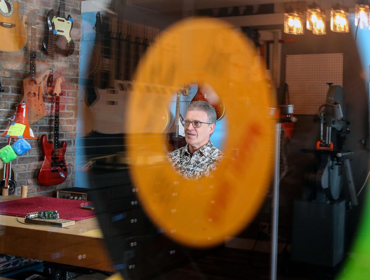 TV Jones founder and president Thomas V. Jones is framed by the middle of a record hanging in the window of his Poulsbo shop as he talks about the different guitars and pickups that they make, on Thursday, April 11, 2024.