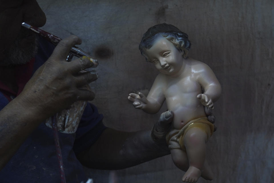 A man paints a repaired a Baby Jesus figure in Mexico City, Wednesday, Jan. 25, 2023. As Mexicans prepare to celebrate "Dia de la Candelaria" or Candlemas people bring in their Baby Jesus figures for major repairs. (AP Photo/Marco Ugarte)