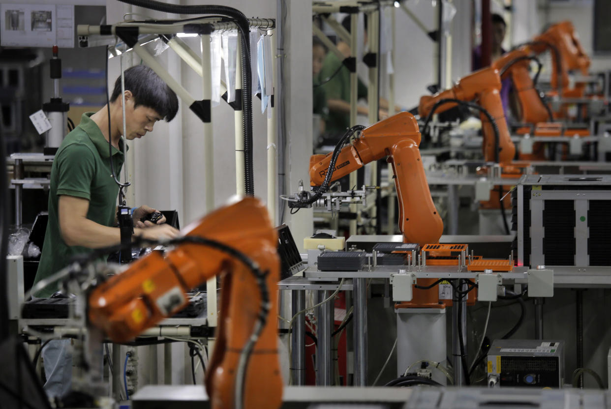 In this Aug. 21, 2015 photo, a Chinese man works amid orange robot arms at Rapoo Technology factory in southern Chinese industrial boomtown of Shenzhen. Factories in China are rapidly replacing those workers with automation, a pivot that's encouraged by rising wages and new official directives aimed at helping the country move away from low-cost manufacturing as the supply of young, pliant workers shrinks. (AP Photo/Vincent Yu)