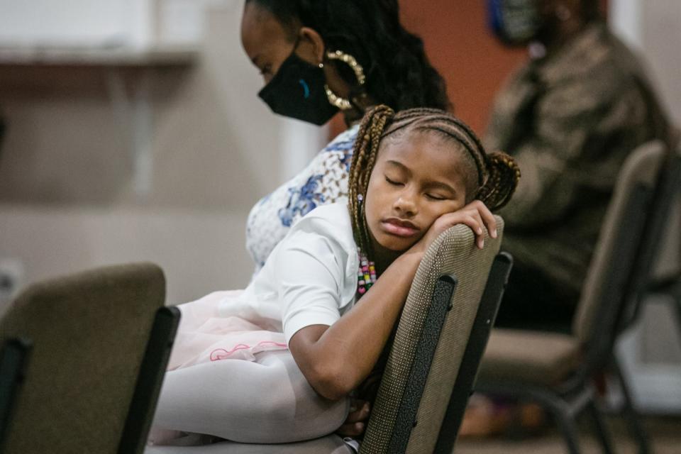 A girl sleeps on a chair.