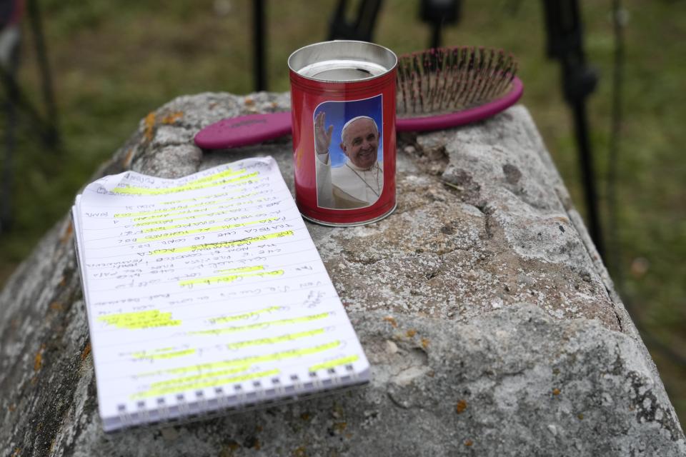 An hair brush and journalist's notebook sit near a candle with a picture of Pope Francis as members of the media set up their gear outside the Agostino Gemelli hospital under the rooms on the top floor normally used when a pope is hospitalised, in Rome, Friday, March 31, 2023. Pope Francis spent another night in hospital after showing a "marked improvement" Thursday and could be released from the hospital in the coming days, the Vatican and his doctors reported. (AP Photo/Gregorio Borgia)