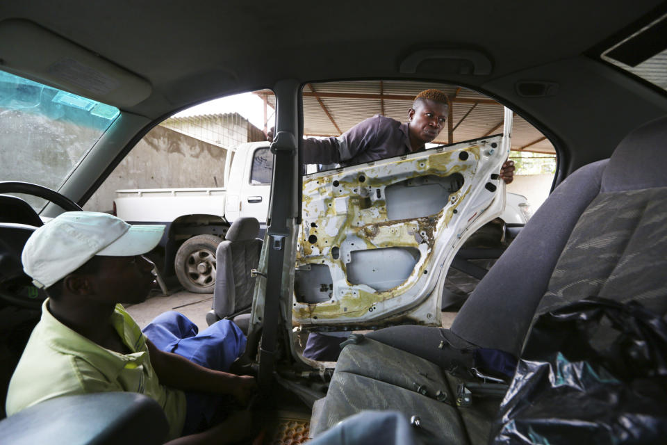 Memory Mukabeta, top, repairs a car at her workshop in Harare, in this Friday, March 5, 2021 photo. Mukabeta runs a car repair shop, a vocation traditionally viewed as a male domain. Mukabeta supports members of her extended family whose livelihoods have been hit by the restrictions caused by the virus. From driving trucks and fixing cars to encouraging girls living with disability to find their places in society, women in Zimbabwe are refusing to be defined by their gender or circumstances, even as the pandemic hits them hardest hardest and imposes extra burdens. (AP Photo/Tsvangirayi Mukwazhi)