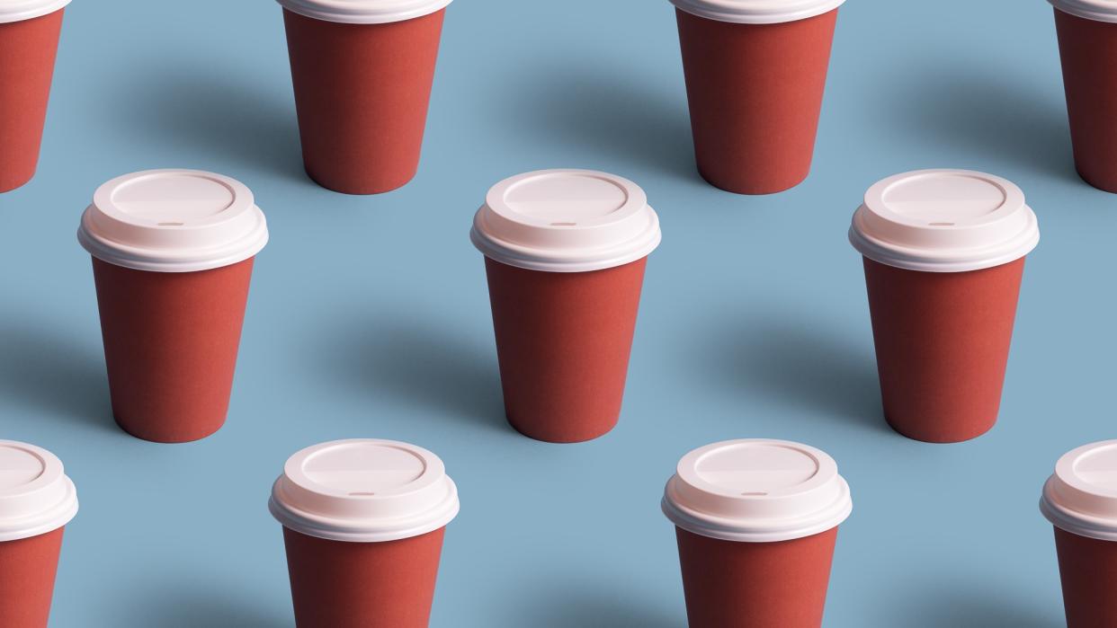 Disposable coffee cups organized in a row over blue background.