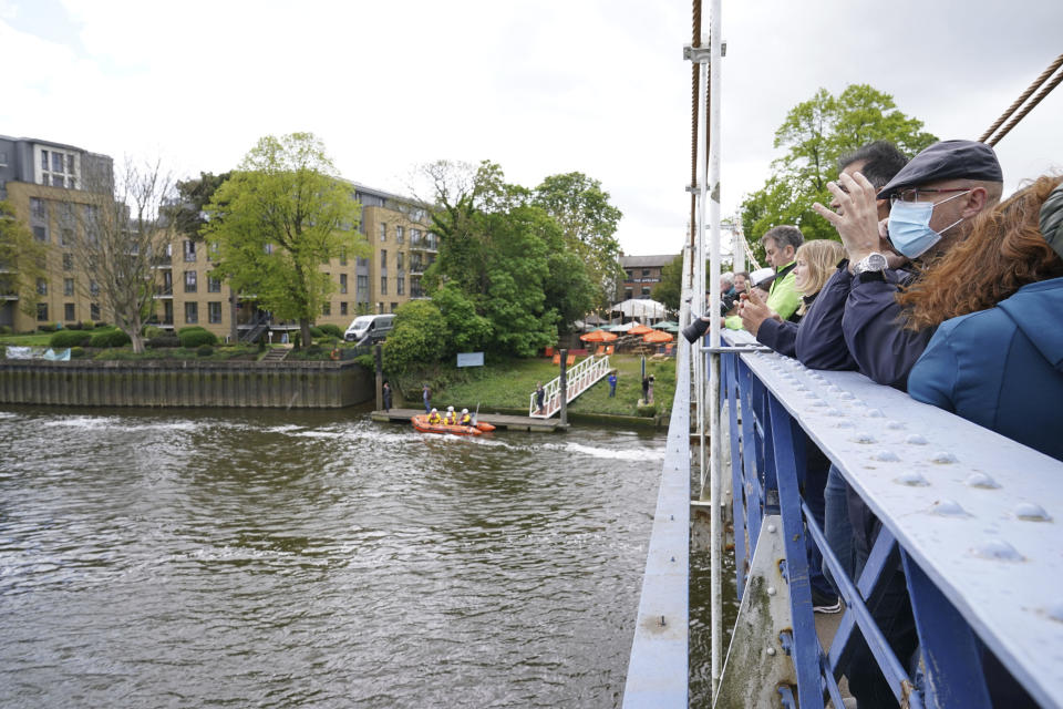 An RNLI boat and crew prepare whilst people gather to spot Minke whale, which was freed on Sunday after it became stuck on Richmond lock's boat rollers but has remained in the Thames, is seen near Teddington Lock in London, Monday, May 10, 2021. A Port of London Authority spokesperson said a whale had never been seen this far up the Thames before, some 95 miles from its mouth. (Yui Mok/PA via AP)