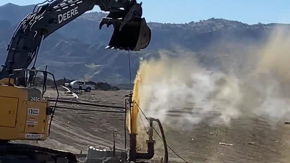 A geyser of brown liquid erupts from a pipe.