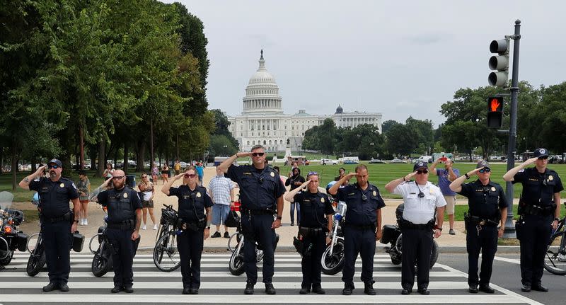 Law enforcement officers salute as a ceremonial procession in honor of a police officer wounded at the Pentagon earlier in the day passes the U.S. Capitol in Washington