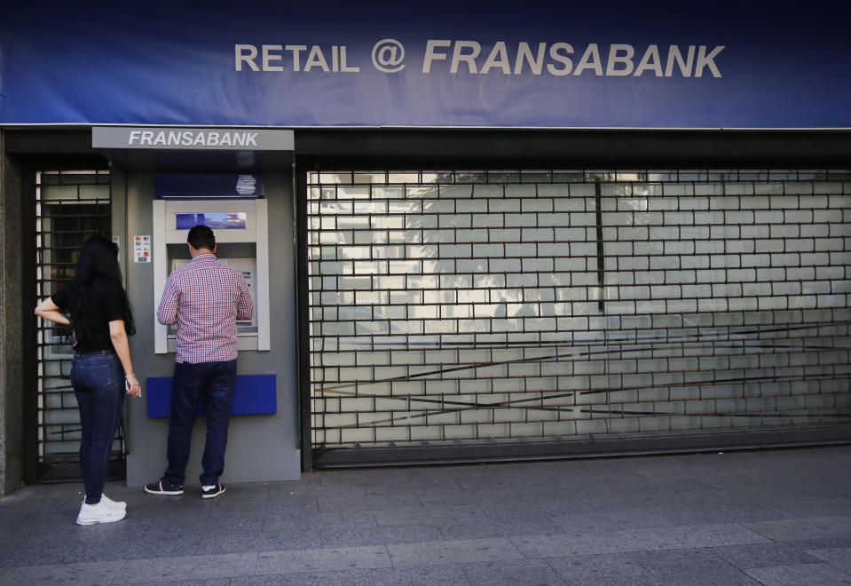 People use ATM outside a closed bank, in Beirut, Lebanon, Wednesday, Oct. 30, 2019. Lebanese banks have been closed for the last two weeks as the government grapples with mass demonstrations that have paralyzed the country, but an even greater crisis may set in when they reopen Friday. (AP Photo/Hussein Malla)