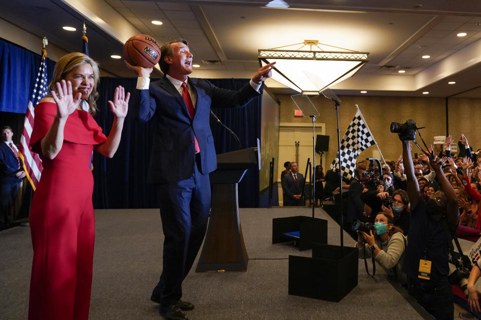 Virginia Gov.-elect Glenn Youngkin tosses a signed basketball to supporters as his wife Suzanne waves at an election night party in Chantilly, Va., early Wednesday, Nov. 3, 2021, after he defeated Democrat Terry McAuliffe. (AP Photo/Andrew Harnik)