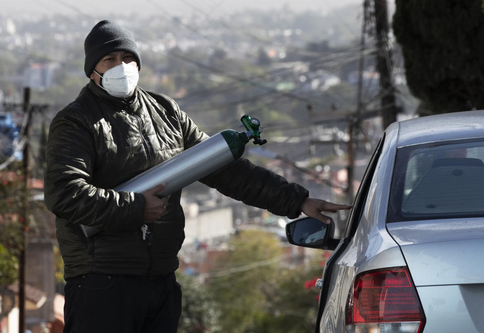 Ricardo Ledesma Carrasco gets into his car after refilling a tank of oxygen at a store for his dad who is being treated for COVID-19 at home in Mexico City, Thursday, Dec. 31, 2020. Carrasco's mother also has COVID-19. (AP Photo/Marco Ugarte)