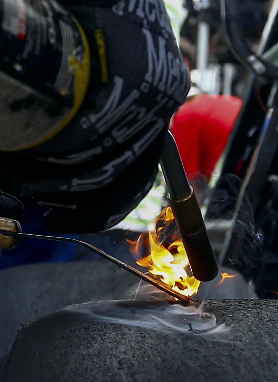 A crew member for Ryan Preece burns rubber off a tire during a NASCAR Cup Series auto race at Talladega Superspeedway, Sunday, April 28, 2019, in Talladega, Ala. (AP Photo/Butch Dill)