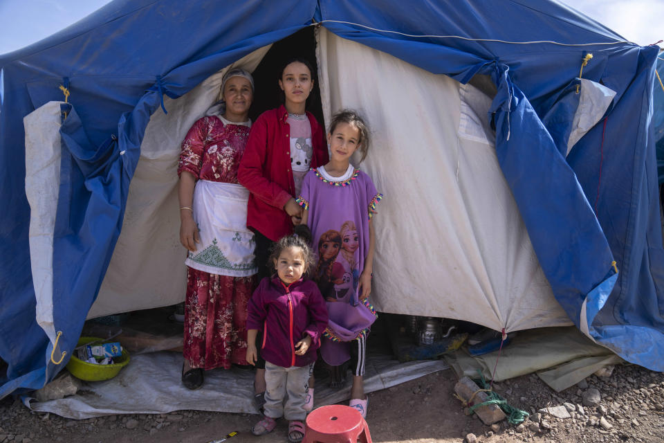 A family displaced by the September earthquake poses for a photograph outside their tent, in Moulay Brahim, outside Marrakech, Morocco, Saturday, Oct. 7, 2023. Morocco has pledged to rebuild from a September earthquake in line with its architectural heritage. Villagers and architects agree that earthquake-safe construction is a top priority. That’s created a push for modern building materials. But the government says it wants to rebuild in line with Morocco’s cultural and architectural heritage. (AP Photo/Mosa'ab Elshamy)