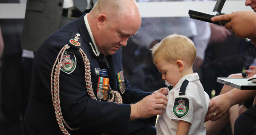 澳洲消防員基頓因為救火殉職，他年僅19個月大的兒子哈維，吸著奶嘴，穿著迷你版消防隊制服，代替父親領取英勇勳章。（圖／翻攝自臉書／NSW Rural Fire Service）