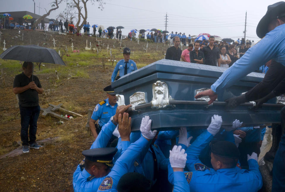 FILE - In this Sept. 29, 2017 file photo, police lift the coffin of fellow officer Luis Angel Gonzalez, during his funeral at the cemetery in Aguada, Puerto Rico. Gonzalez died when he tried to navigate a river crossing in his car during the passing of Hurricane Maria. (AP Photo/Ramon Espinosa, File)