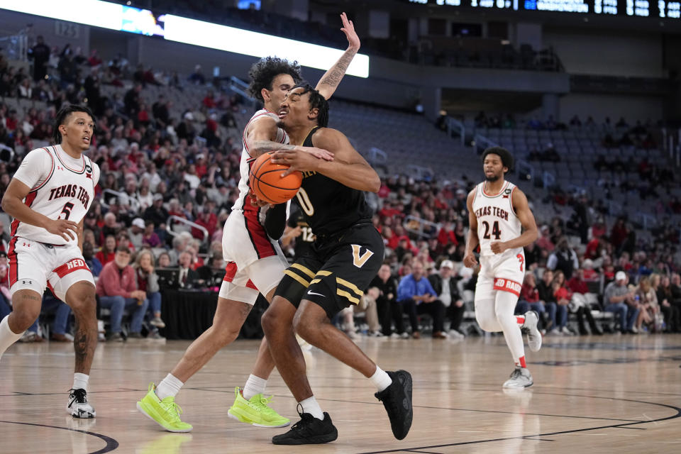 Vanderbilt guard Tyrin Lawrence (0) is fouled driving to the basket by Texas Tech guard Pop Isaacs, center left, in the second half of an NCAA college basketball game in Fort Worth, Texas, Saturday, Dec. 16, 2023. (AP Photo/Tony Gutierrez)