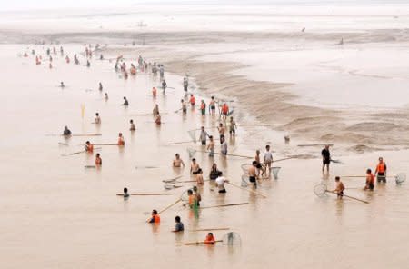 People fish along the bank of the Yellow River as the Sammenxia Dam discharges flood waters downstream, in Pinglu, Shanxi province, July 9, 2015. REUTERS/China Daily