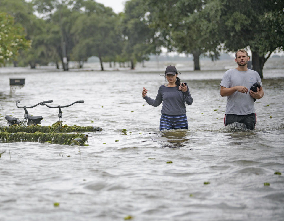 Collen Schiller and Wesley Vinson wade through storm surge from Lake Pontchartrain on Lakeshore Drive in Mandeville, La., Saturday, July 13, 2019. The waves are caused by the wind and storm surge from Hurricane Barry in the Gulf of Mexico. Mandeville is on the north shore of the lake while New Orleans is on the south shore. (AP Photo/Matthew Hinton)