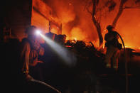 Firefighters coordinate efforts at a burning property while battling the Fairview Fire Monday, Sept. 5, 2022, near Hemet, Calif. (AP Photo/Ethan Swope)