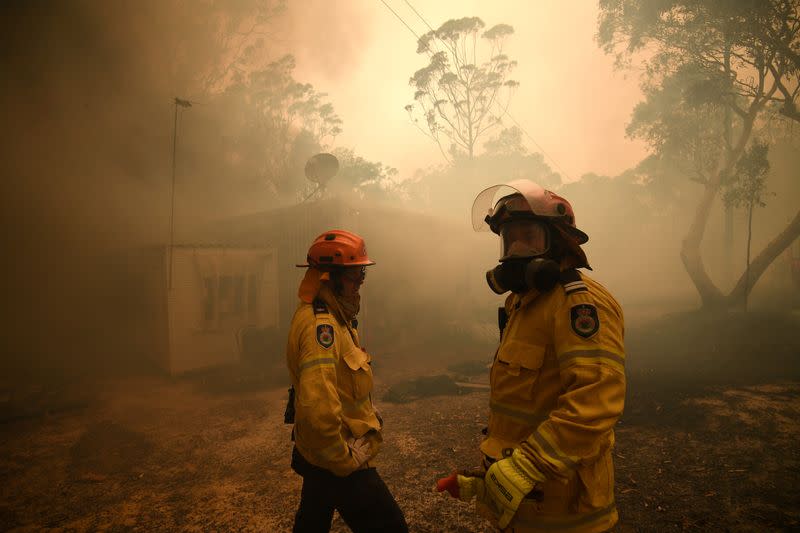 El Servicio Rural de Bomberos de Nueva Gales del Sur y los equipos de bomberos y rescate de Nueva Gales del Sur trabajan para proteger una propiedad en Kyola Road en Kulnura a medida que el incendio de Three Mile se acerca a Mangrove Mountain, Australia