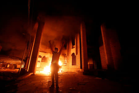 FILE PHOTO: An Iraqi protester gestures in front of the burnt Iranian Consulate in Basra, Iraq September 7, 2018. To match Analysis IRAQ-POLITICS/ REUTERS/Essam al-Sudani/File Photo