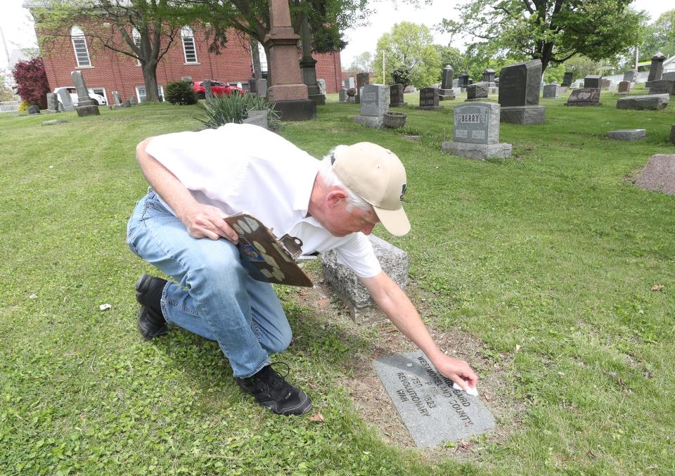 Jim Weyrick cleans off the headstone of Revolutionary War veteran George Baird at Ellet Cemetery in Akron. The cemetery was established in 1823.