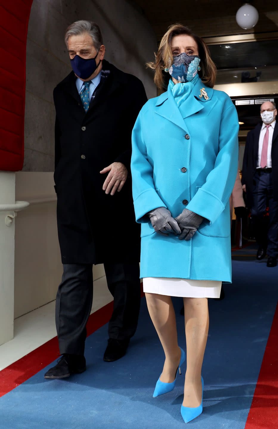 <p>Nancy Pelosi, the Speaker of the House, followed the monochromatic theme of the day and chose a cheerful shade of turquoise for her coat, scarf, and matching heels for the ceremony. Leather gloves, a well-placed brooch, and patterned mask complete the look. </p>