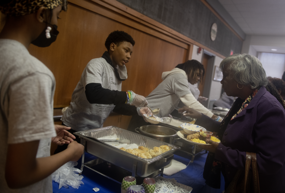 Volunteers from CARE (Children Always Resisting Enemies) of Portage County help serve breakfast, including Julian Jones, 13, pouring gravy over a biscuit, at the Martin Luther King Jr. Prayer Breakfast on Saturday at Kent United Church of Christ.