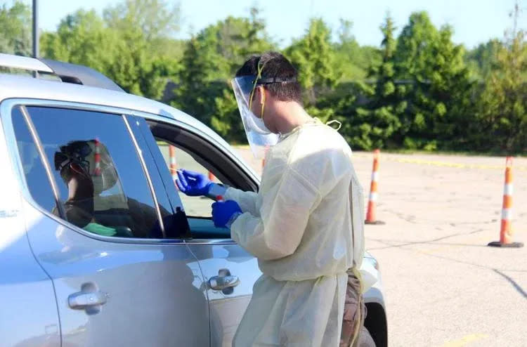 A health care worker conducts a drive-up COVID-19 test.