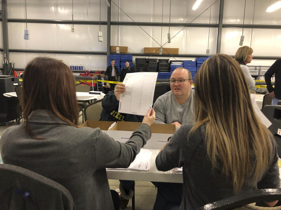 Daviess County Clerk Leslie McCarty, left, holds up a ballot for Deputy Clerk Kyle Chandler to inspect during a recount for Kentucky state House district 13 on Saturday, Feb. 2, 2019, in Owensboro, Ky. Democrat Jim Glenn won the race by one vote in November. But the Republican-controlled legislature has ordered a recount at the request of GOP candidate DJ Johnson (AP Photo/Adam Beam)