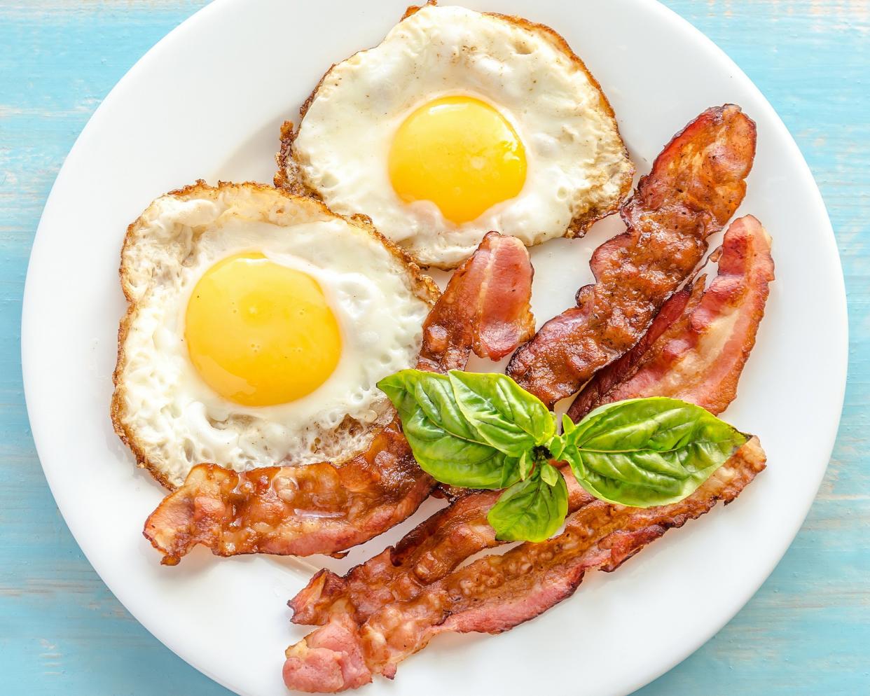 fried eggs with bacon on the wooden table
