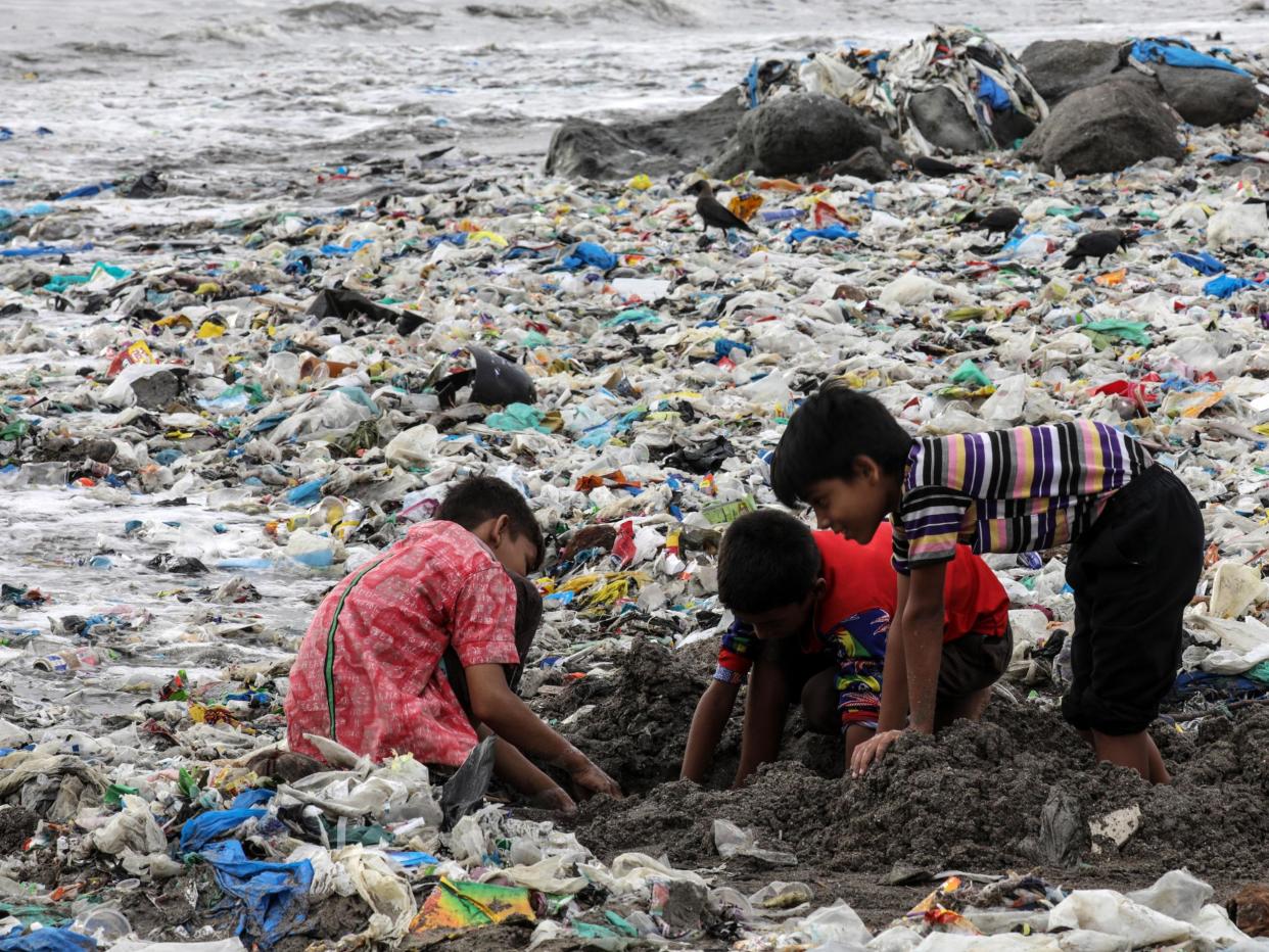 Indian children play amid leftovers and plastic waste, near the Arabian Sea coast at Mahim beach in Mumbai (EPA)