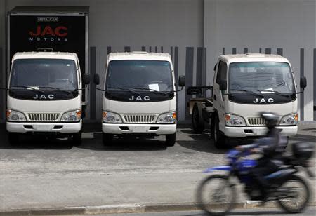 A motorcyclist rides past Chinese JAC trucks displayed at a store in Sao Paulo October 30, 2013. REUTERS/Paulo Whitaker